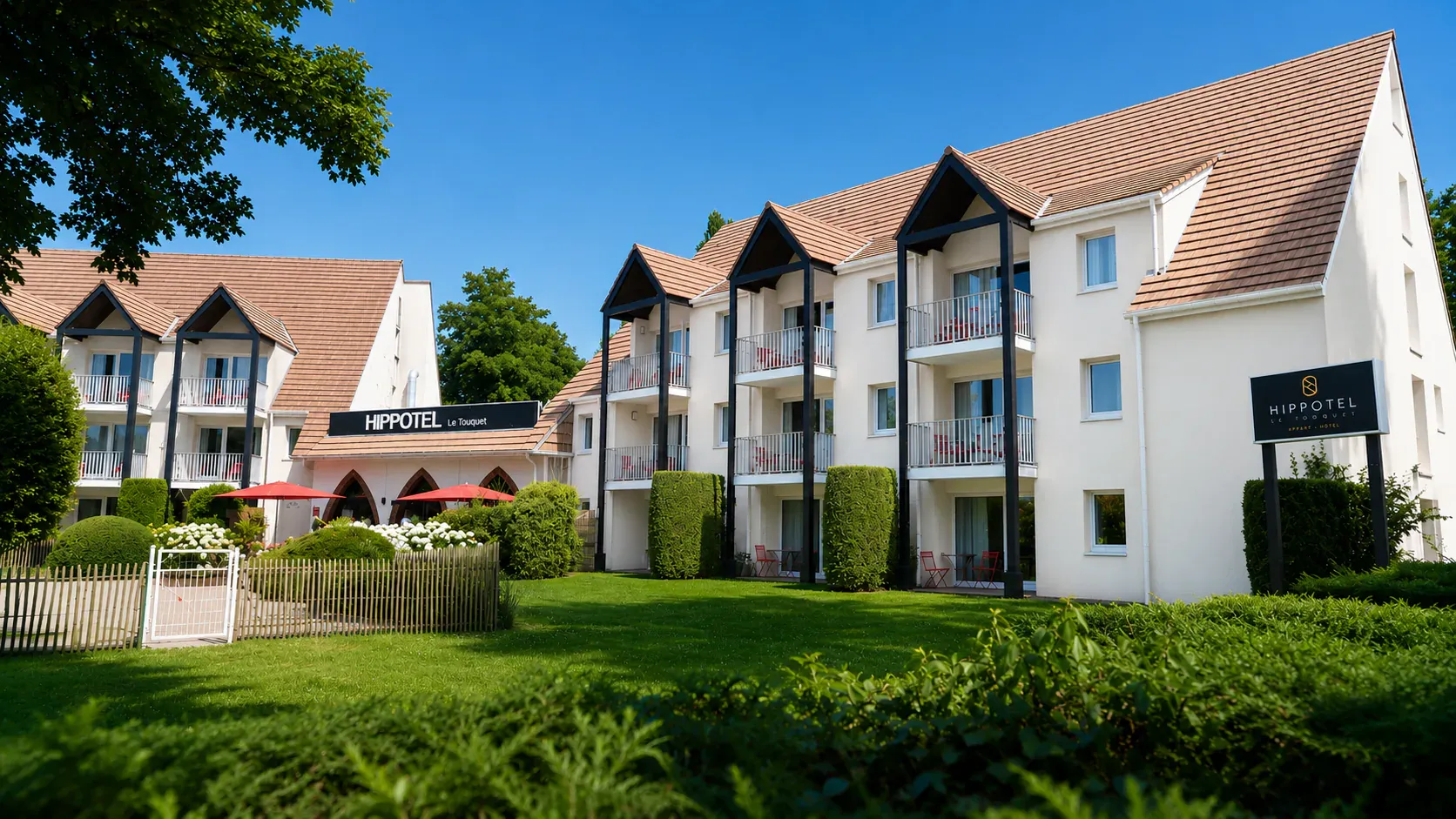La façade de l'Hippotel et ses balcons, vue depuis la pelouse du jardin
